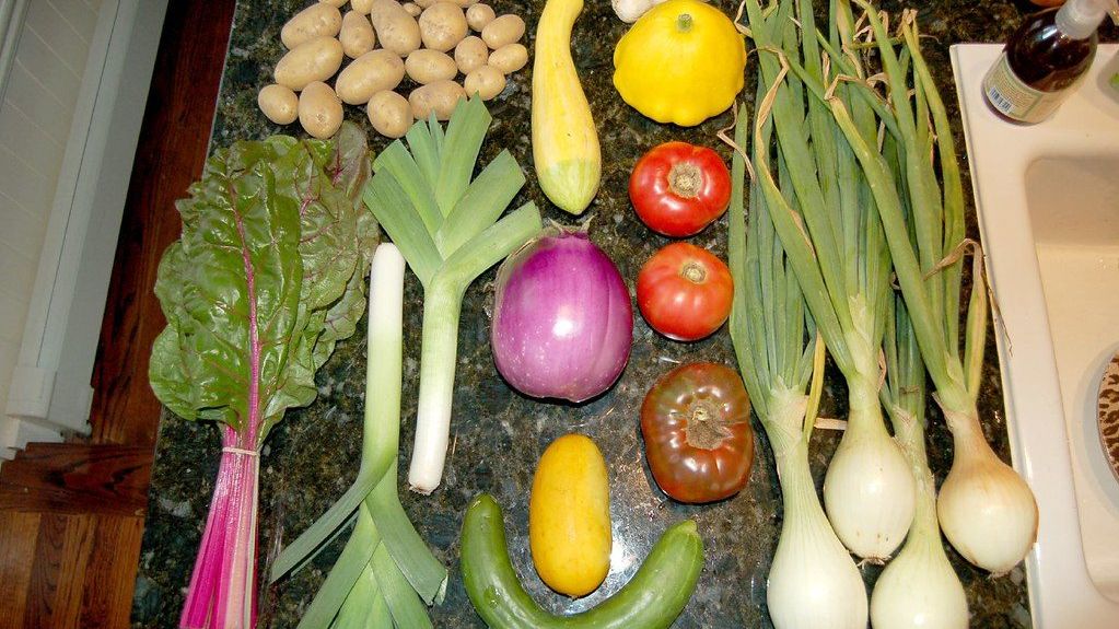 Weekly vegetables laid out for meal prep: potatoes, leeks, onions, chard and squash